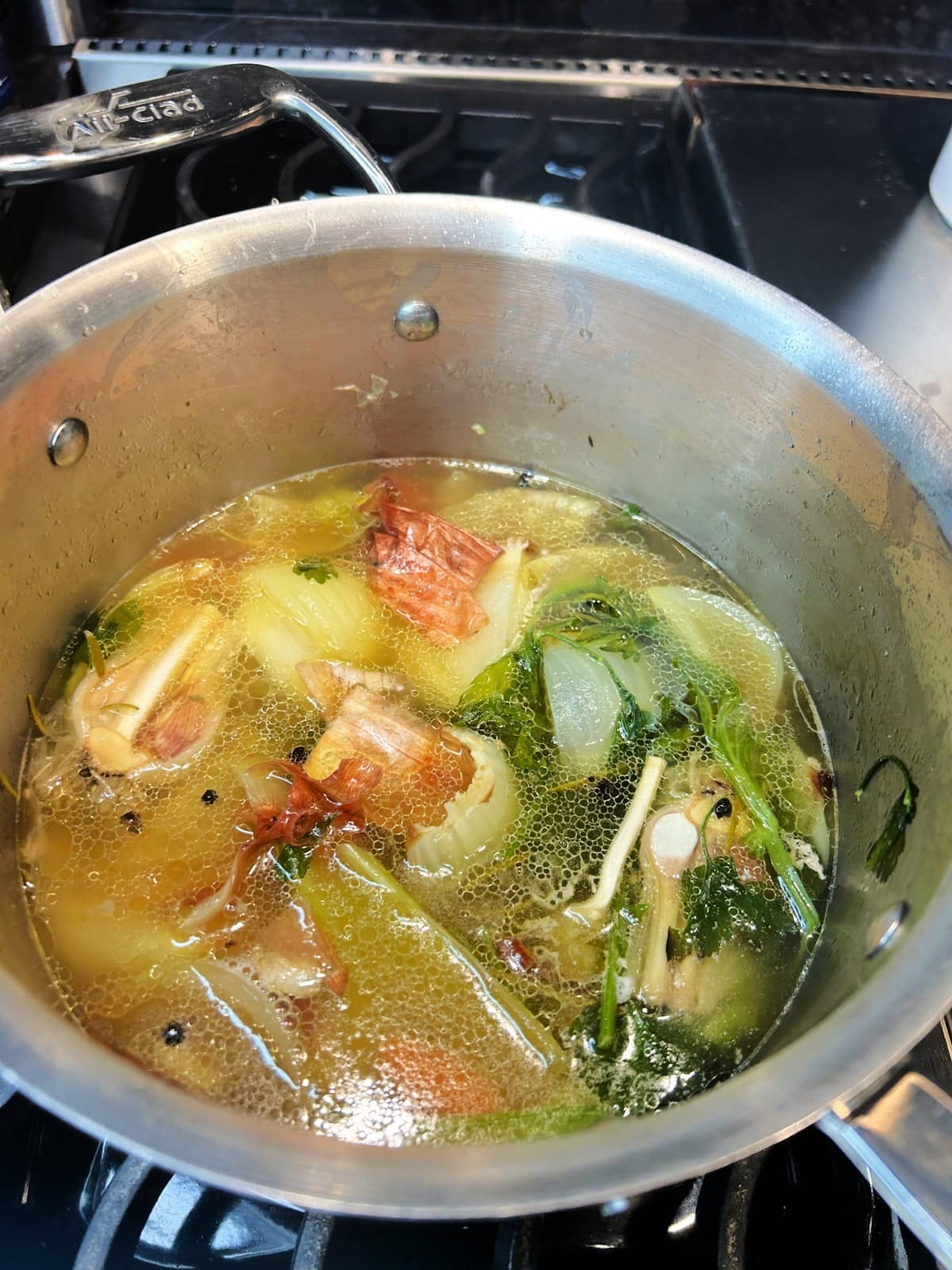 Chicken thighs and broth simmering in a saucepan