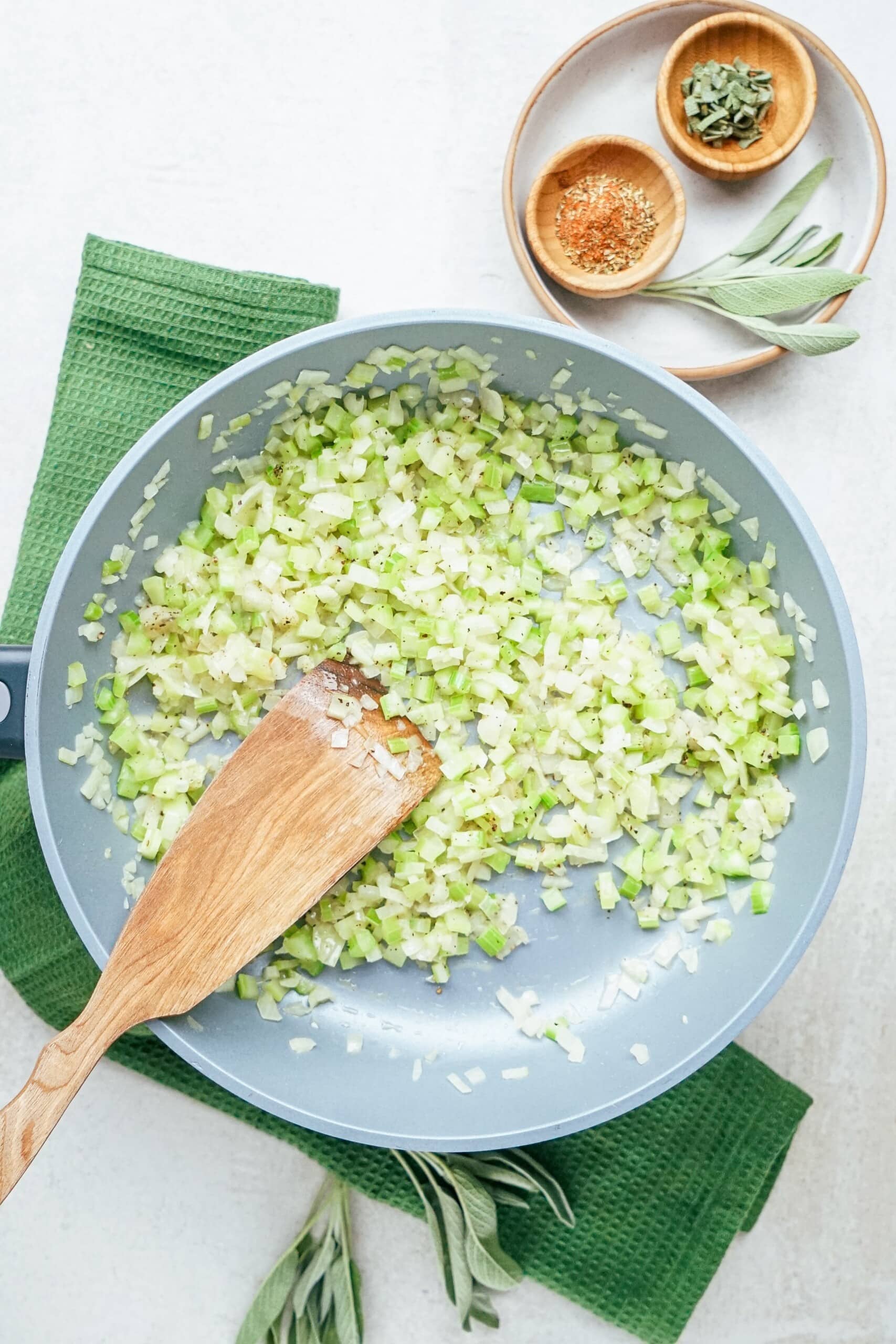 sautéed onions and celery in a skillet with wooden spatula