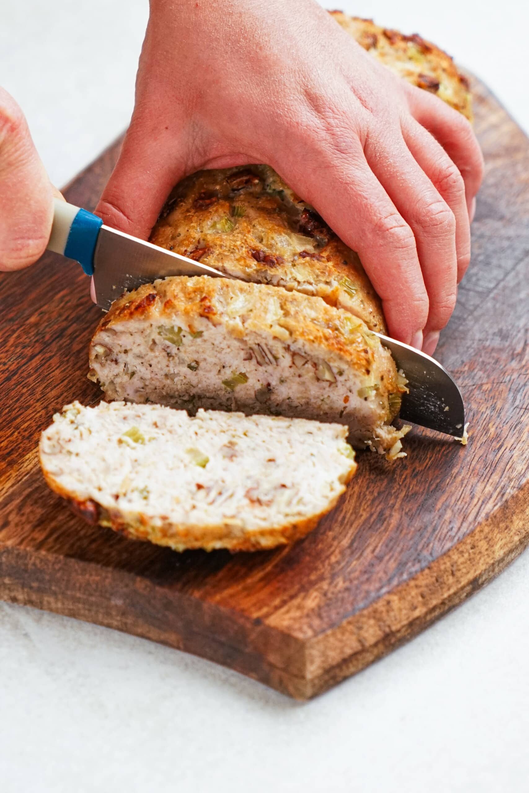 woman's hand slicing meatloaf with a knife