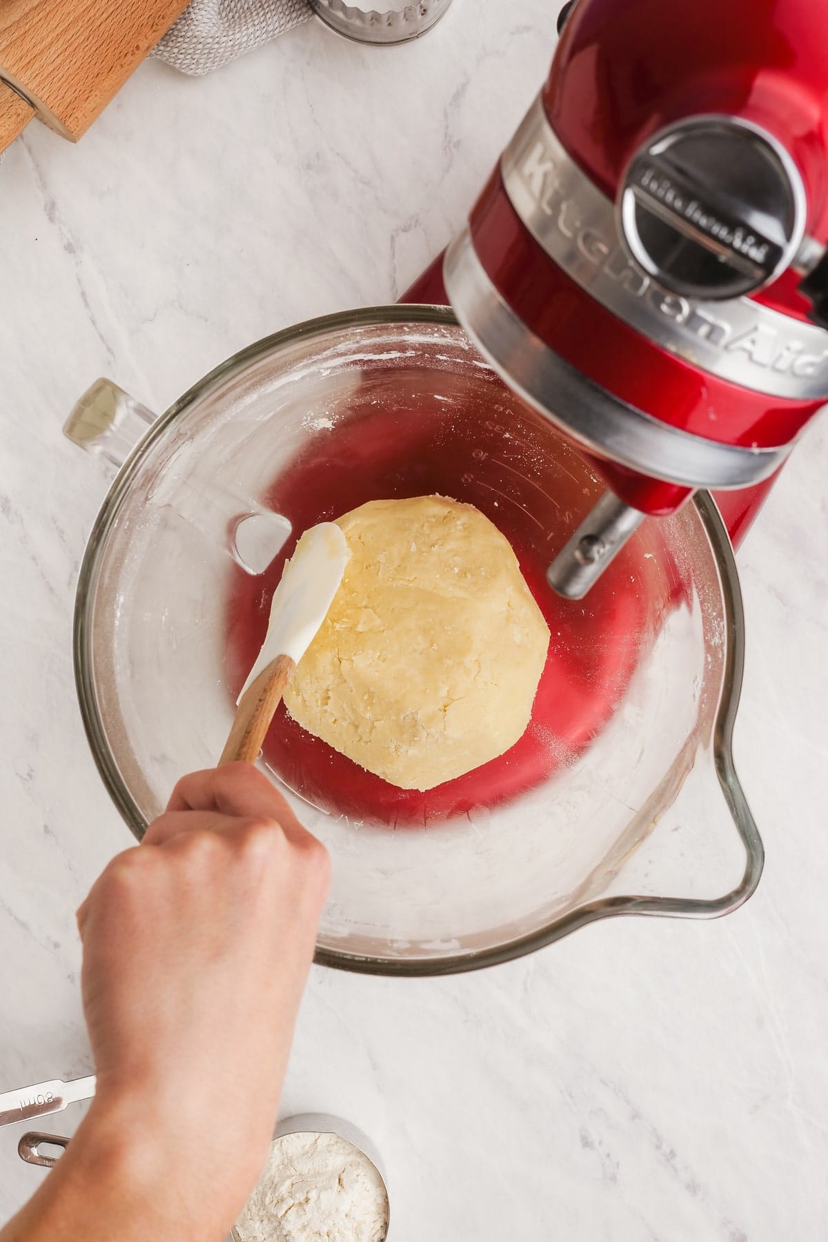 cookie dough being formed into ball with a rubber spatula while in a stand mixer bowl