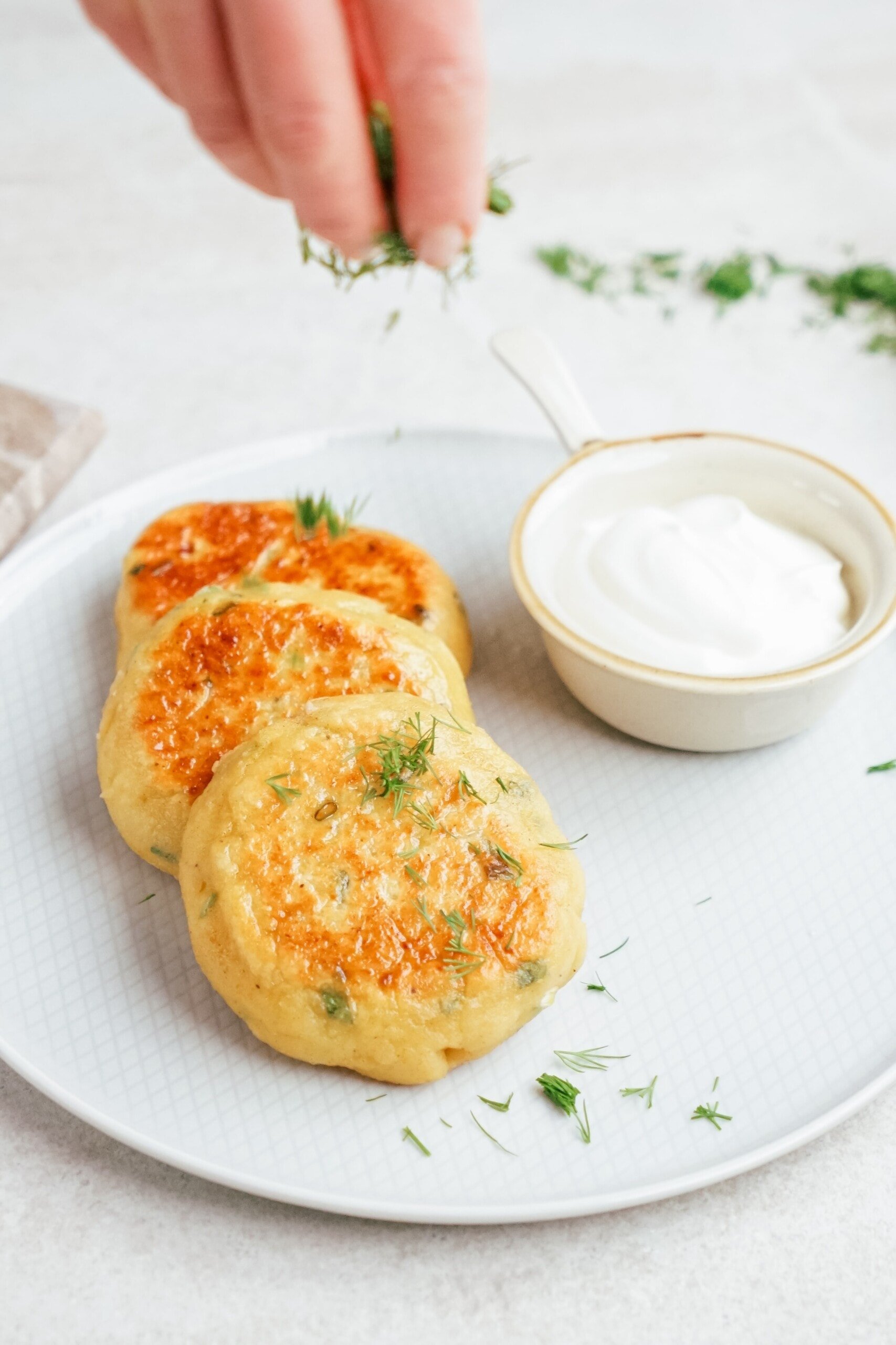 potato patties on a plate with sour cream in a little dish
