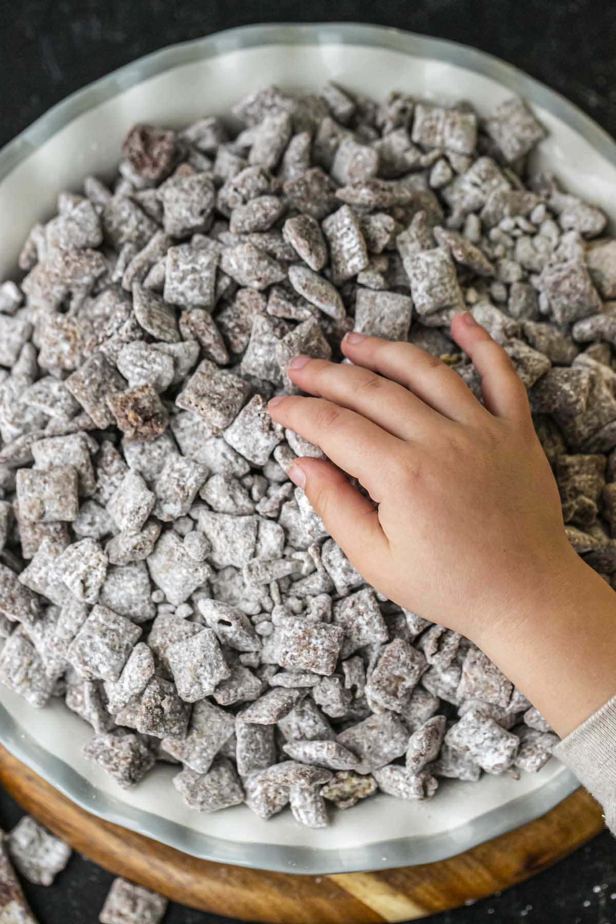 puppy chow in bowl with child's hand