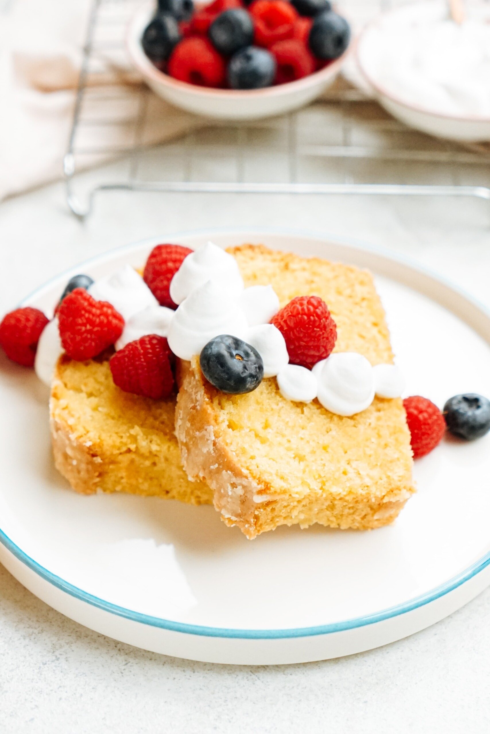 lemon pound cake slices on a plate with whipped Cream and berries