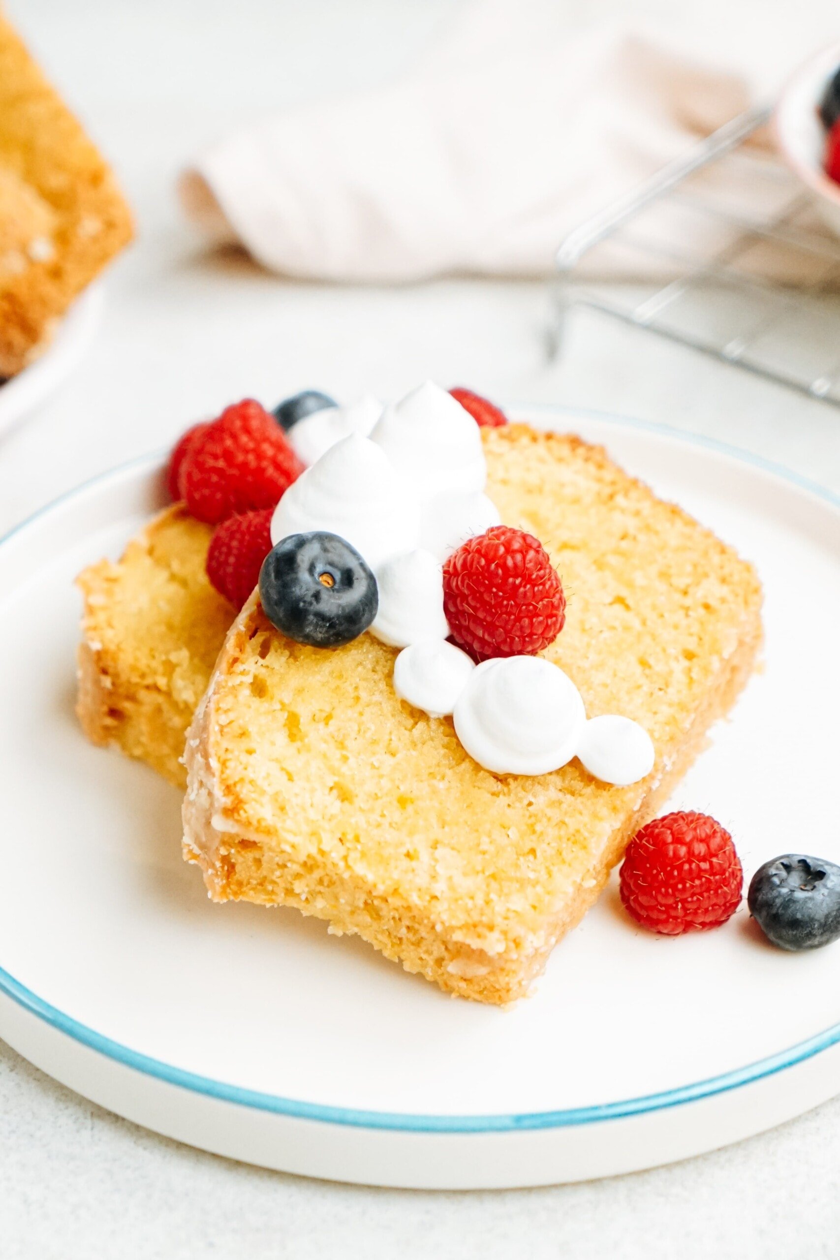 slices of lemon pound cake on a plate with berries and cream 