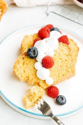 Meyers lemon pound cake slices on a plate with whipped cream and berries