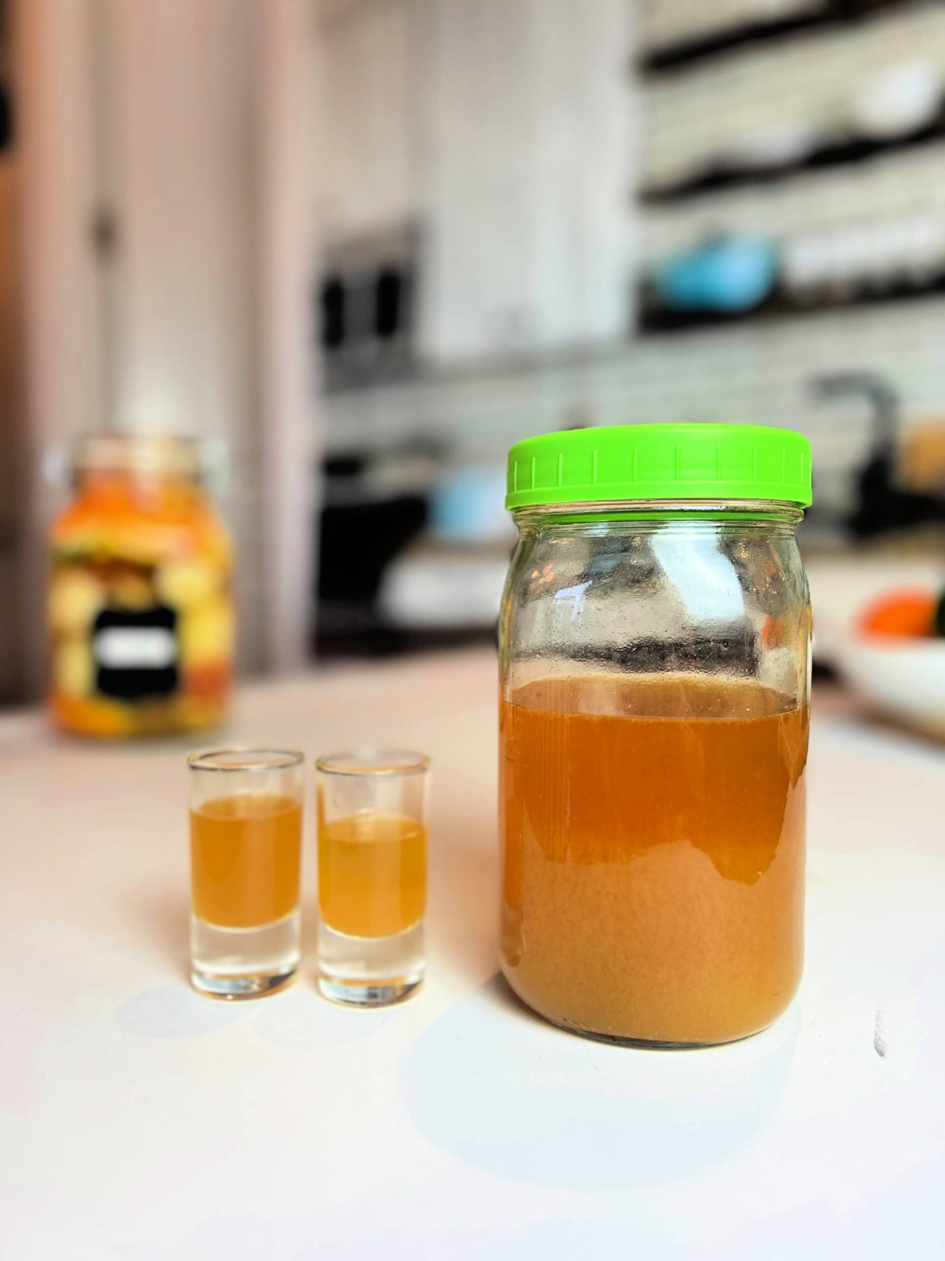 Fire Cider in jar and shot glasses on counter