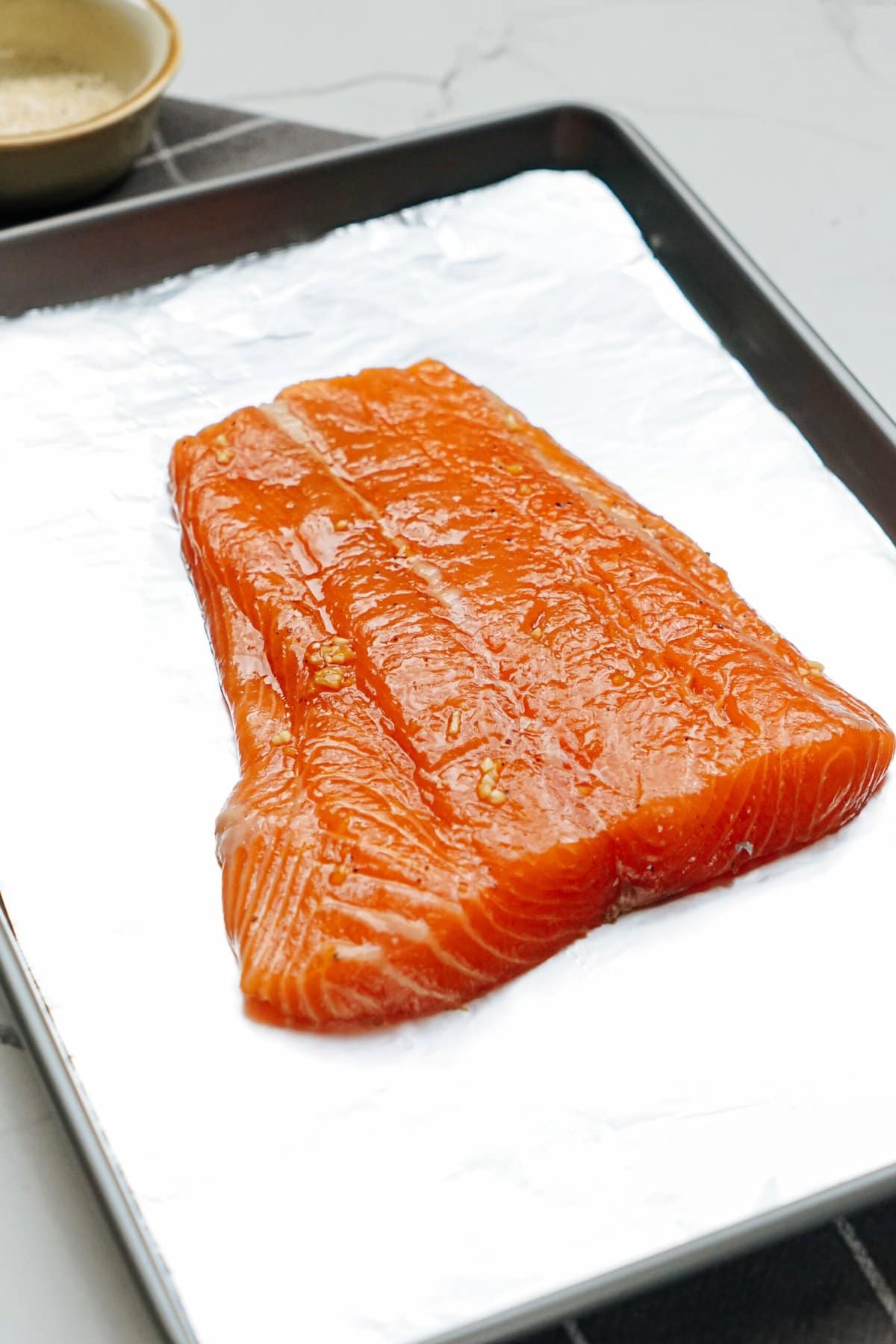 Salmon fillet on a baking sheet, ready to be cooked.