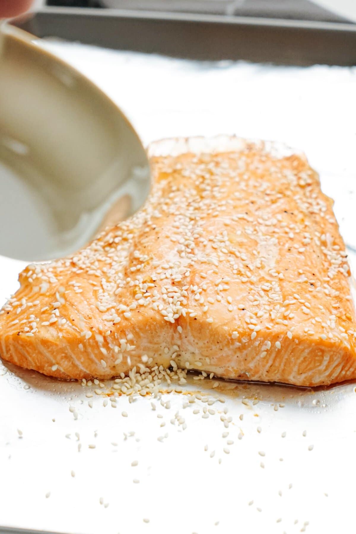Salmon sprinkled with sesame seeds on a baking sheet.