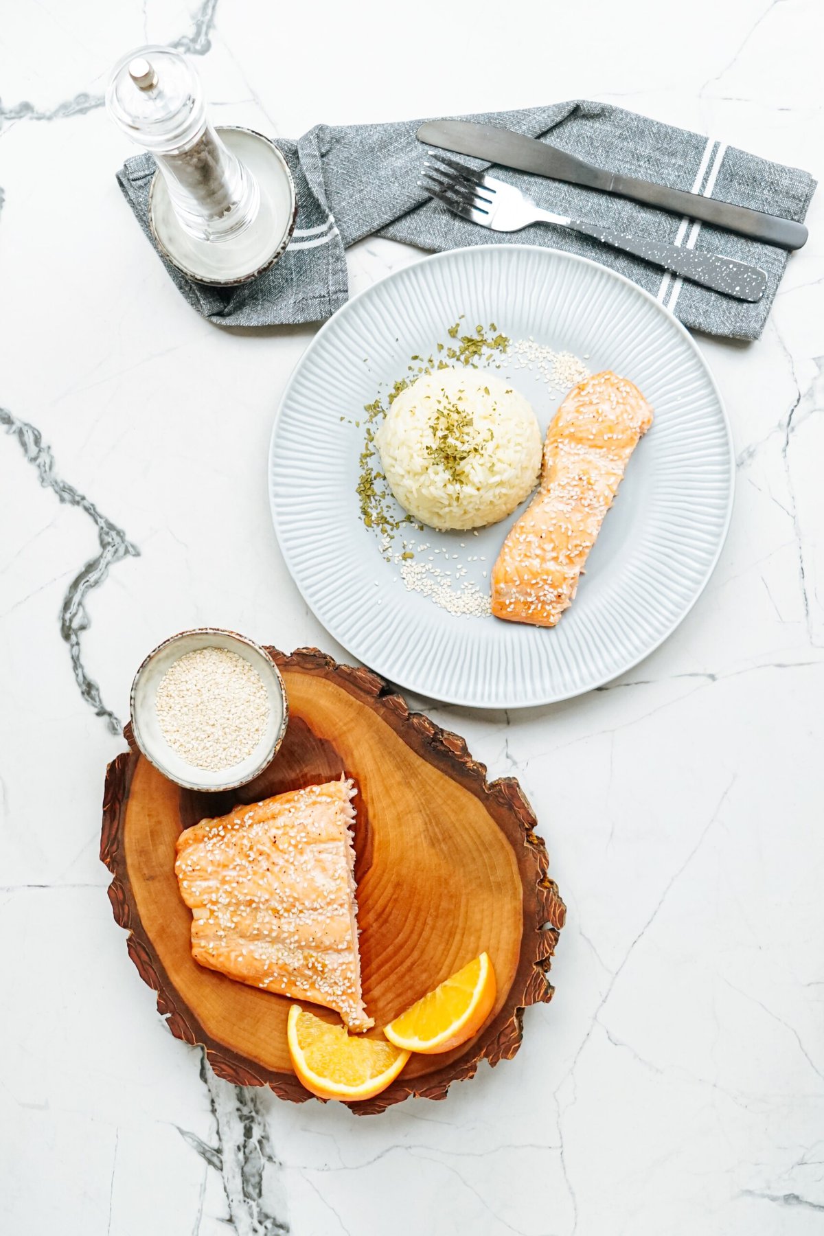 Salmon on a plate with rice and orange slices.
