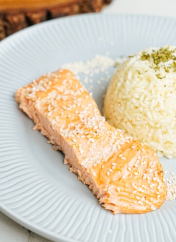 Salmon on a plate with rice and sesame seeds.