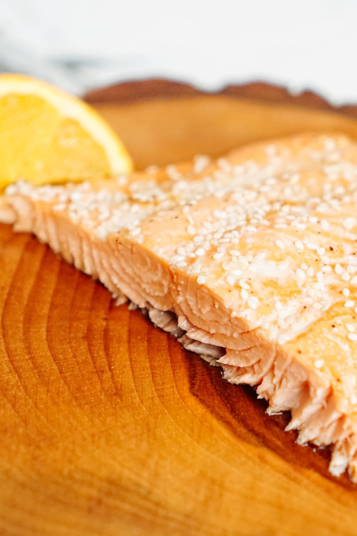 Salmon with sesame seeds on a wooden cutting board.