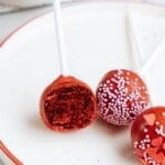 cake pops on a plate, one of them showing the inside of the cake pop