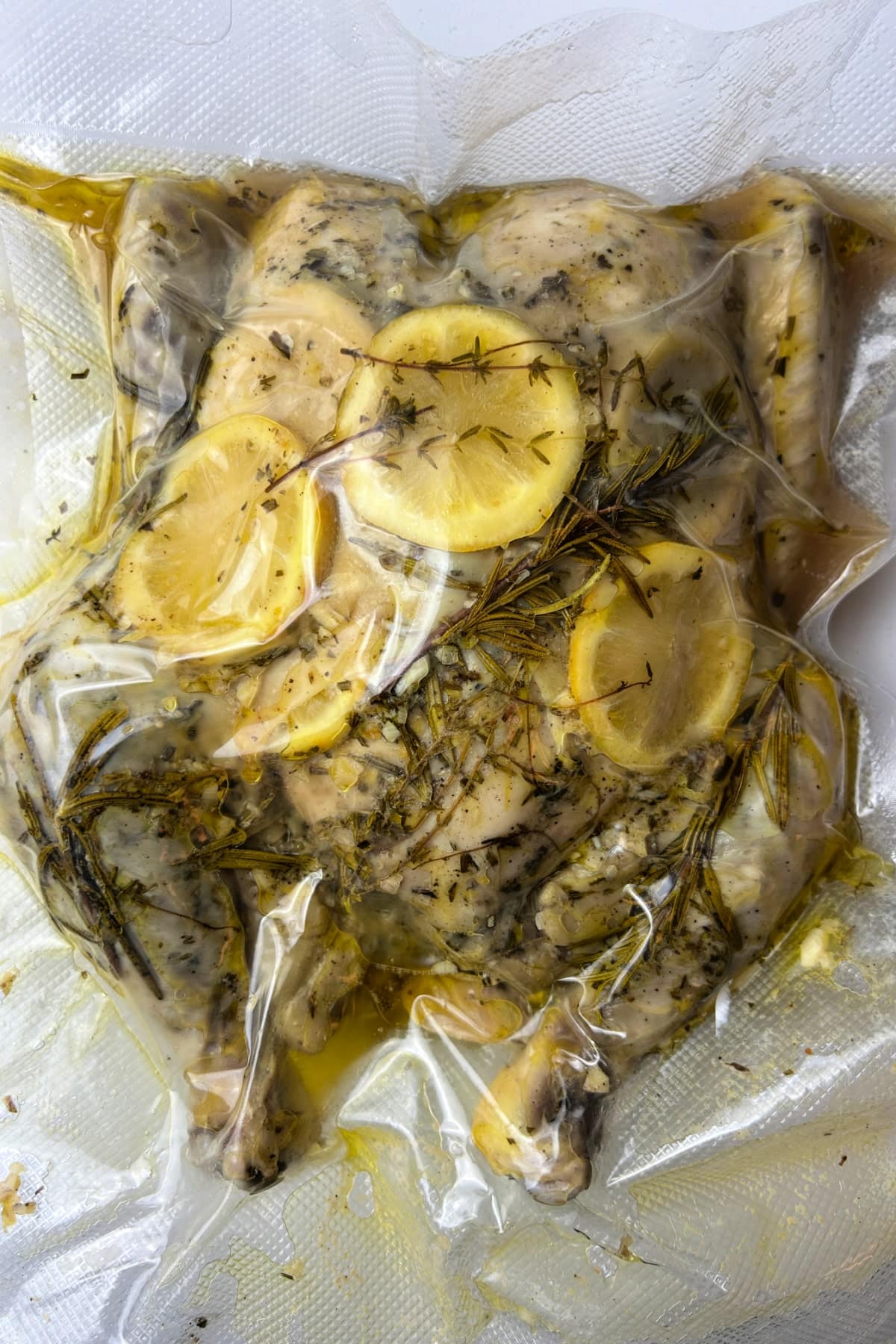 spatchcock chicken in sous vide vacuum sealed bag with lemons and herbs