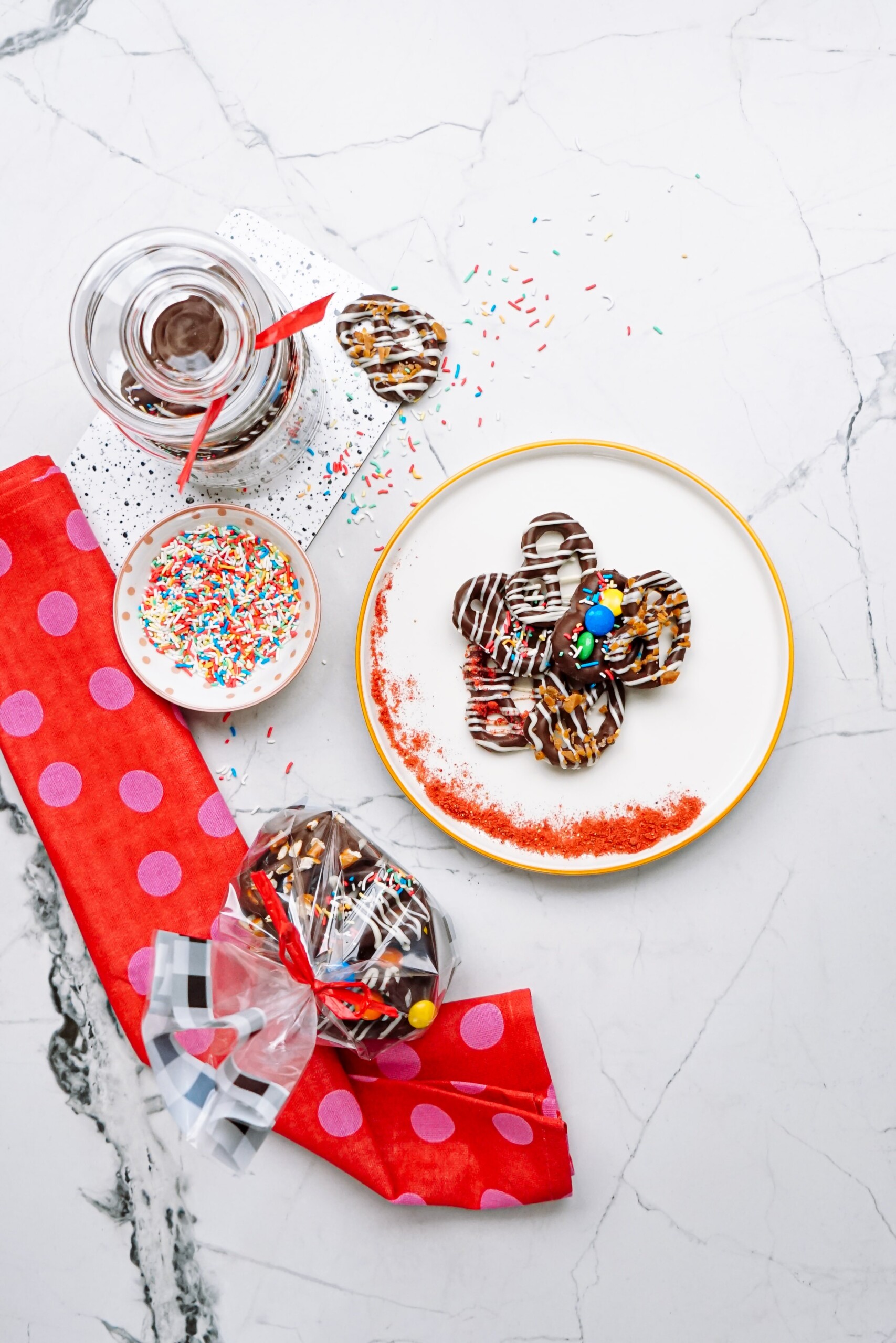 A plate with chocolate pretzels and sprinkles on it.