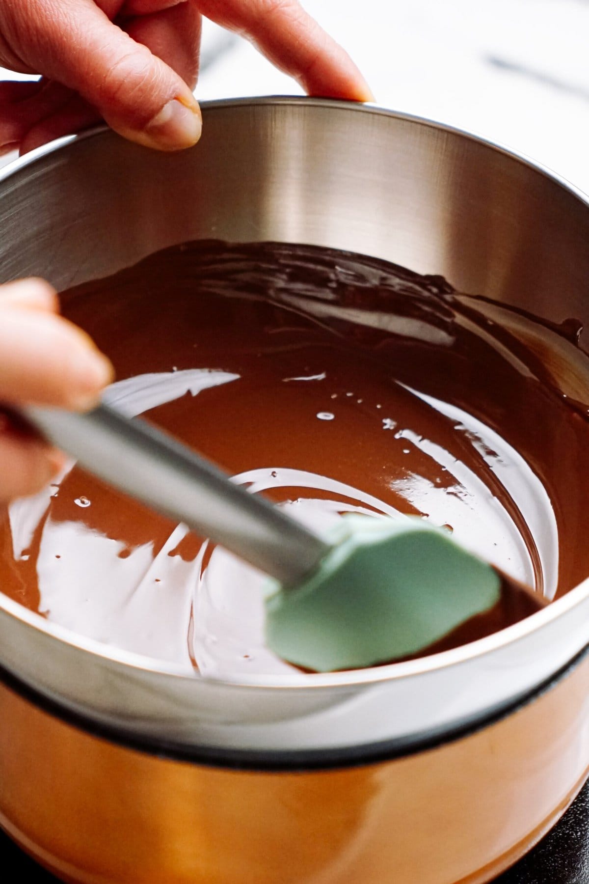 A person stirring melted chocolate a bowl.