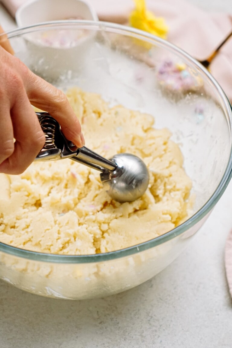 Scooping cake from a glass bowl with a cookie scoop.