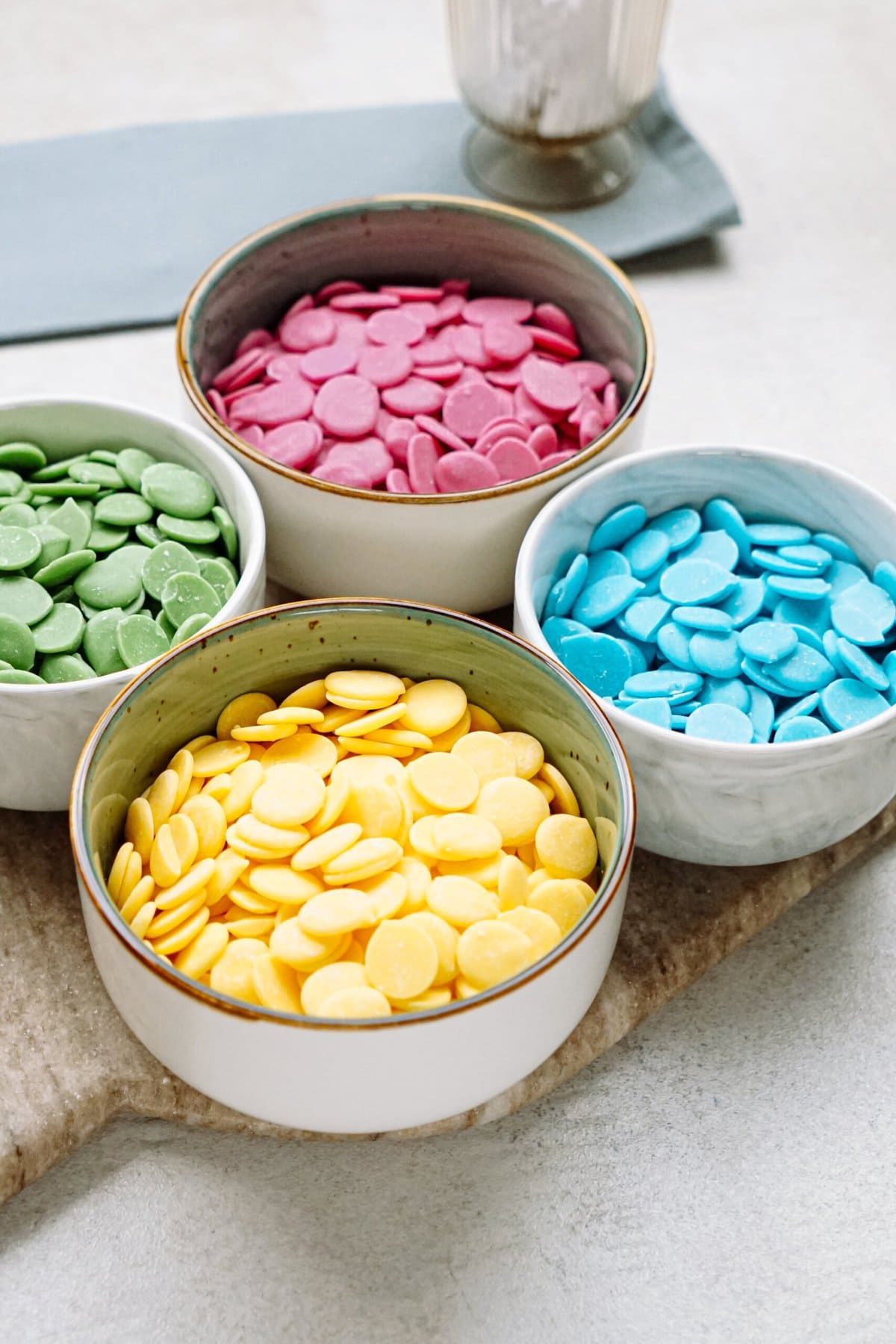Four bowls filled with colorful candy melts arranged on a countertop.