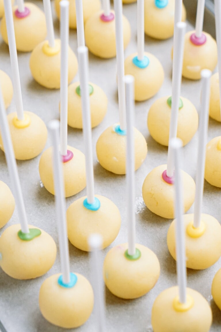 Uncoated cake pops on sticks arranged on a tray.