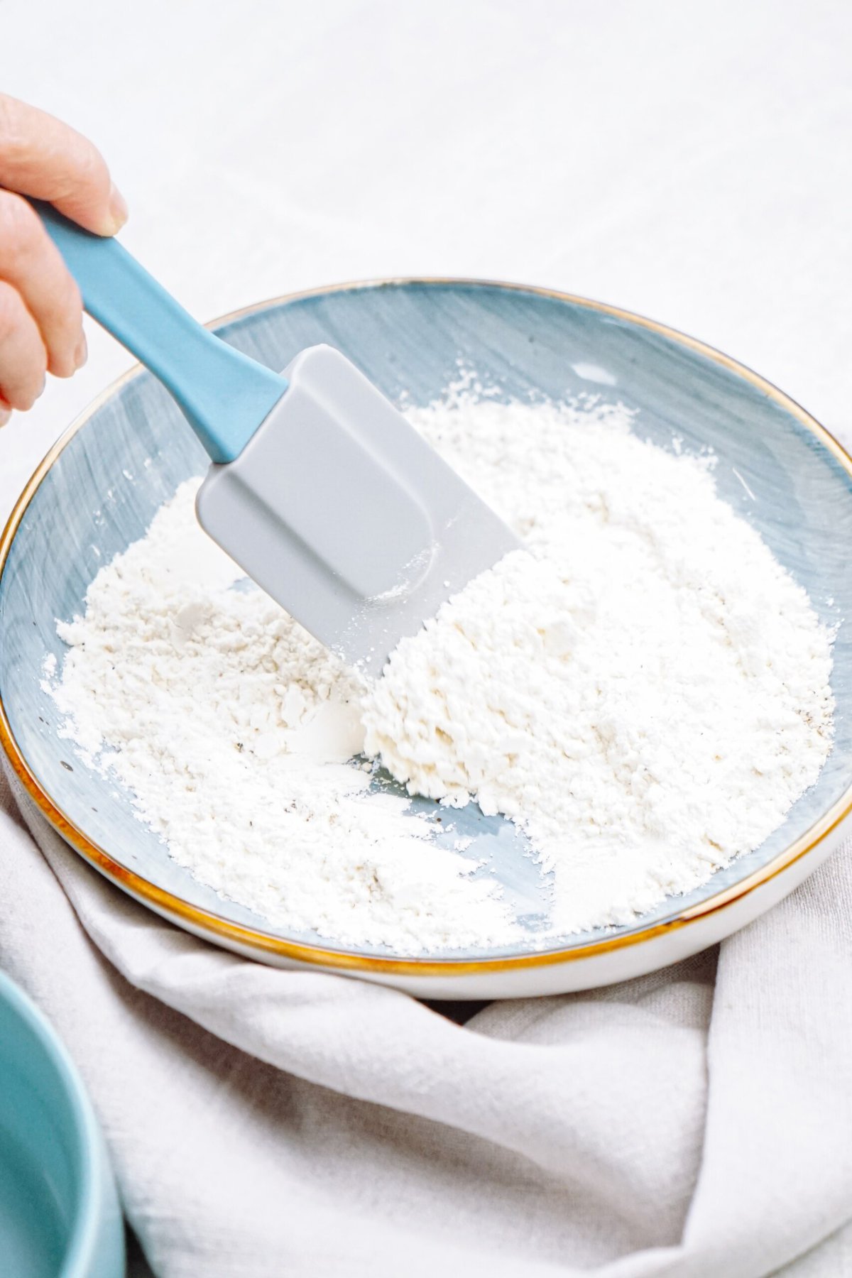 A person using a spatula to mix flour in a bowl.