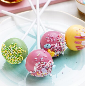 A plate holding colorful cake pops decorated with sprinkles.