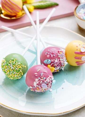 A plate holding colorful cake pops decorated with sprinkles.