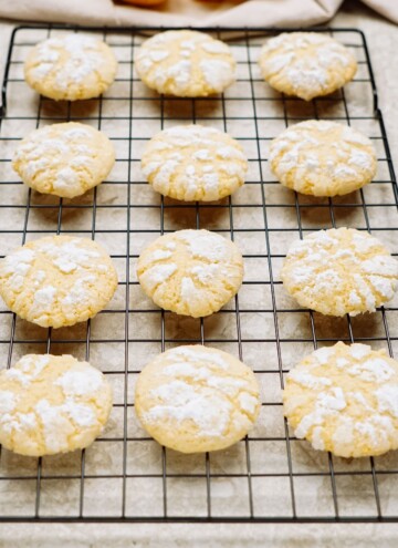 Freshly baked cookies dusted with powdered sugar cooling on a wire rack.