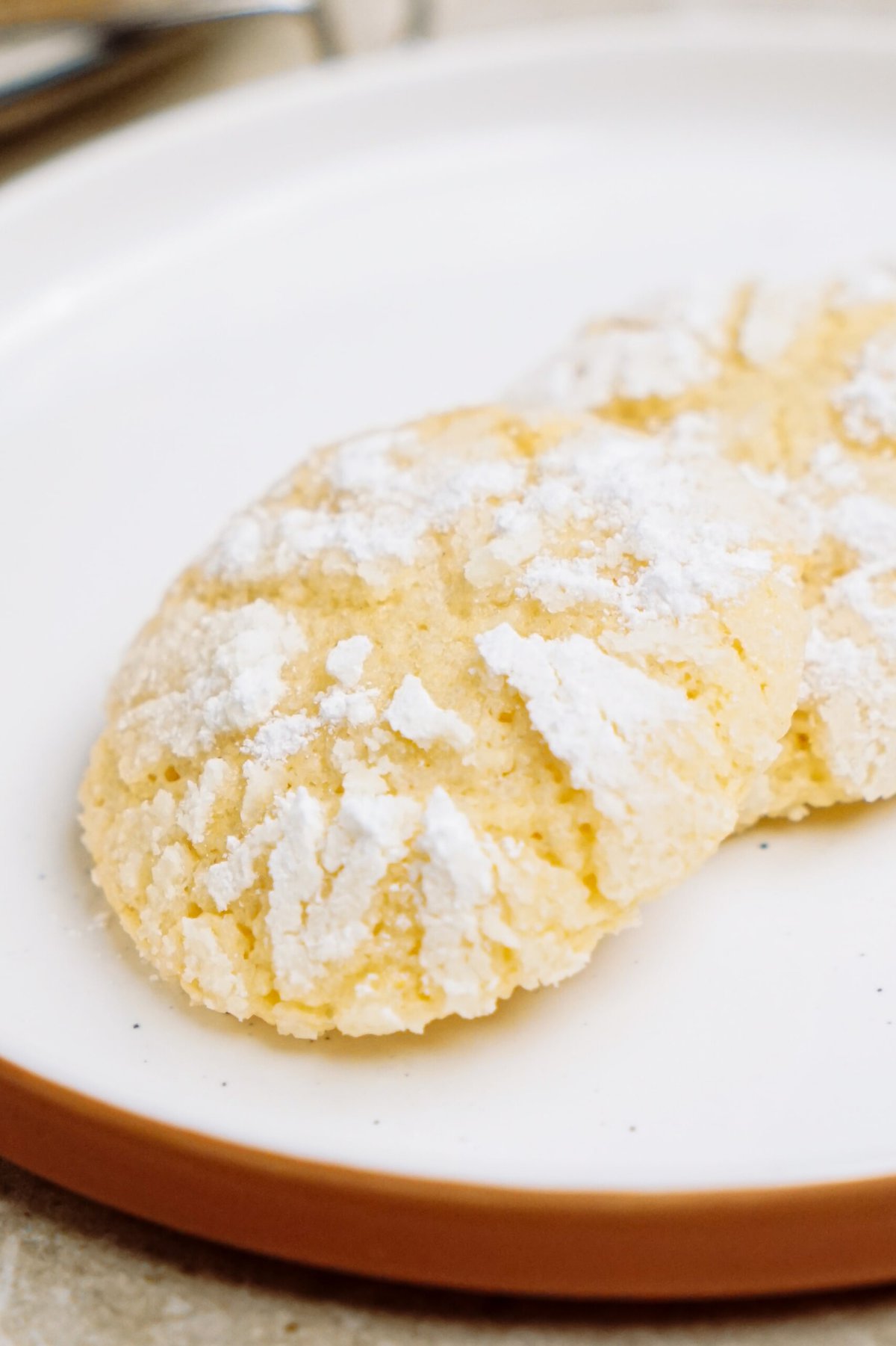 Powdered sugar-dusted lemon crinkle cookies on a plate.