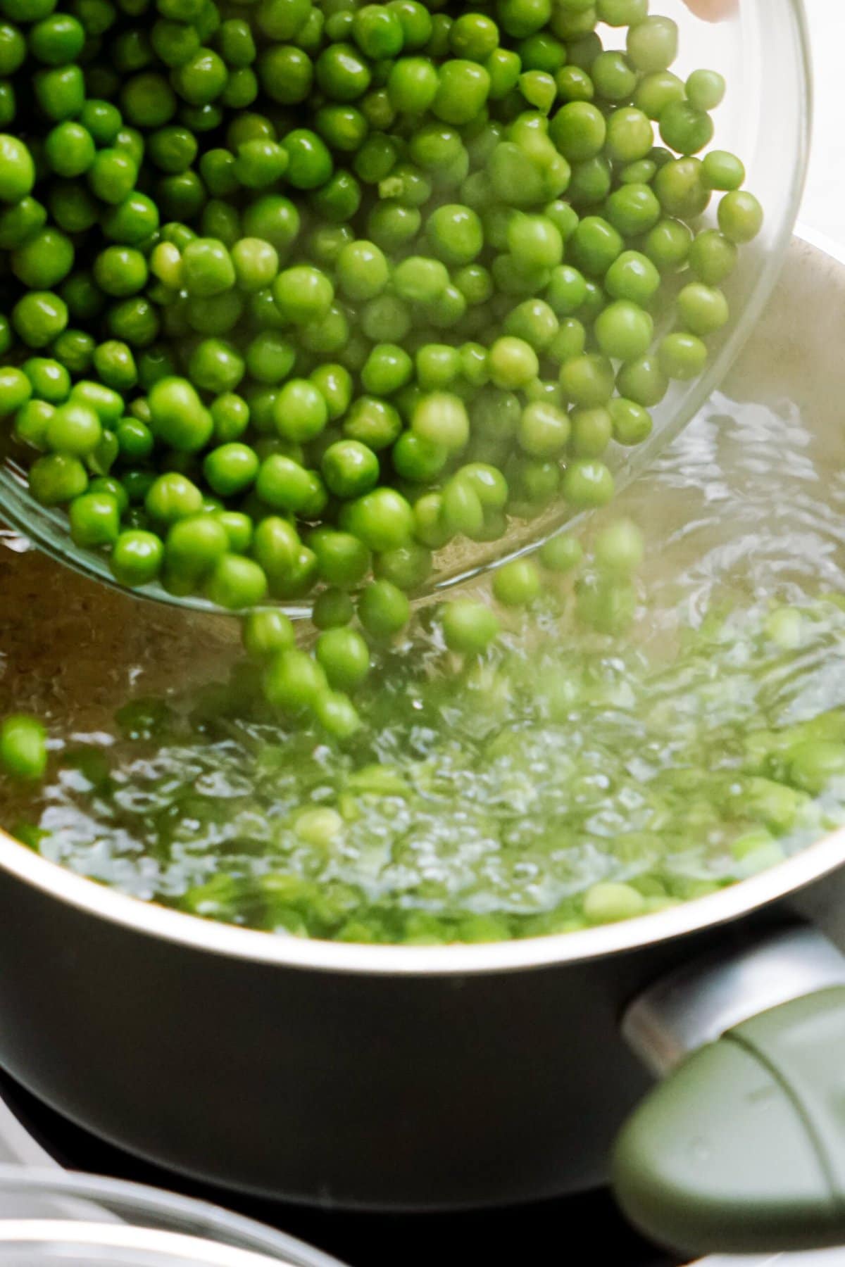 Fresh green peas being prepared for a pea salad, boiling in water.