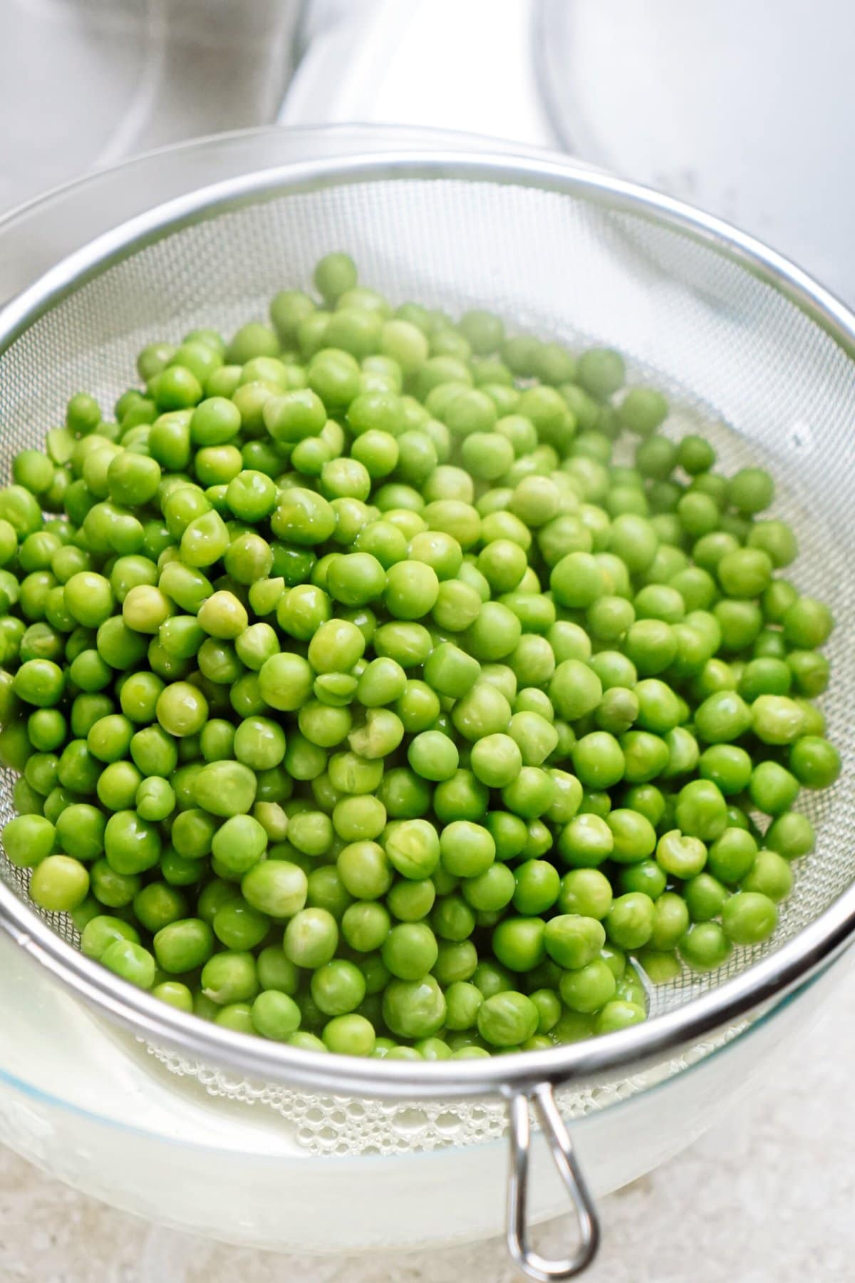 Fresh green peas for a pea salad in a colander.