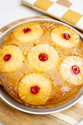 Pineapple upside-down cake with cherries on a serving plate.