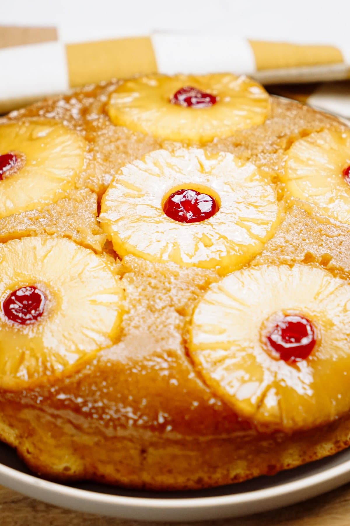 Pineapple upside-down cake with cherries on a plate.
