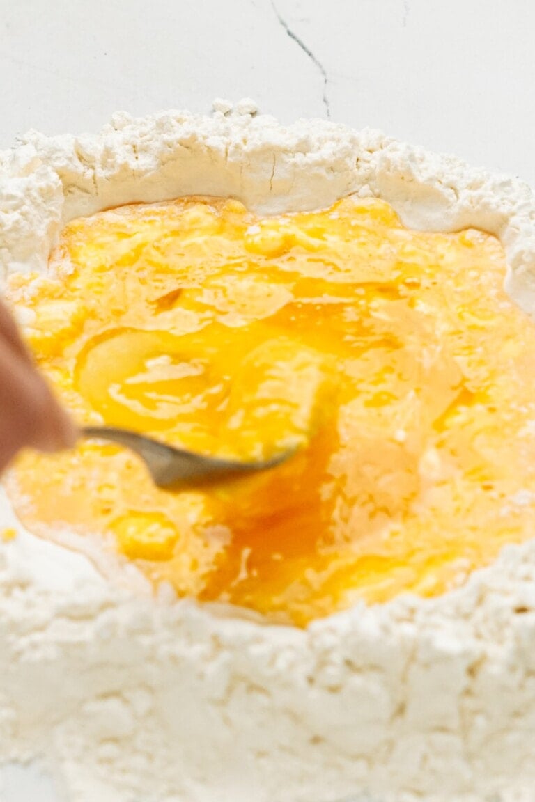 a person using a fork to scramble eggs in flour