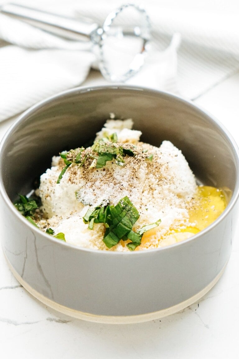 A bowl with eggs, ricotta and herbs in it.