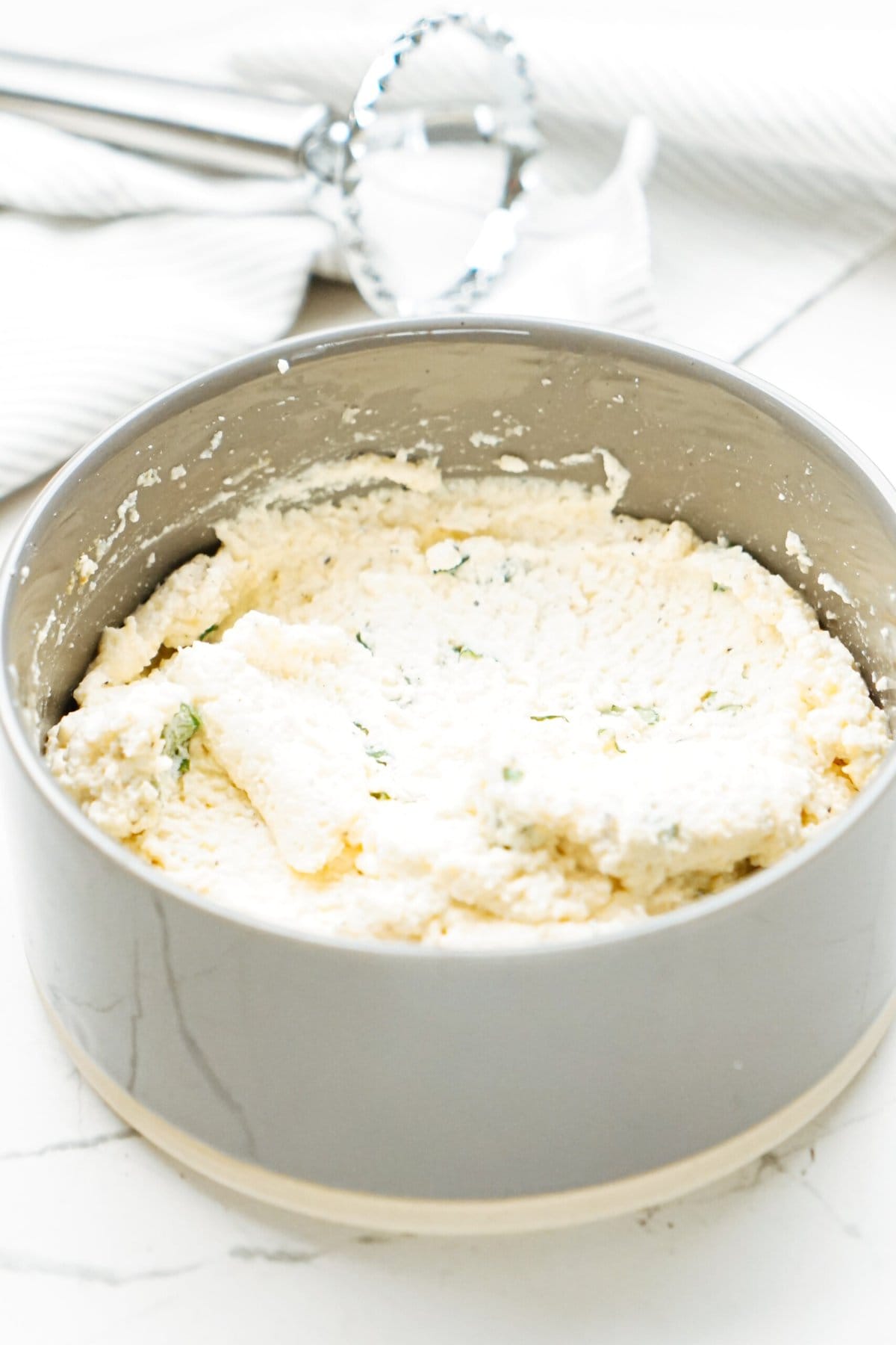 A bowl filled with a mixture of cheese and herbs.