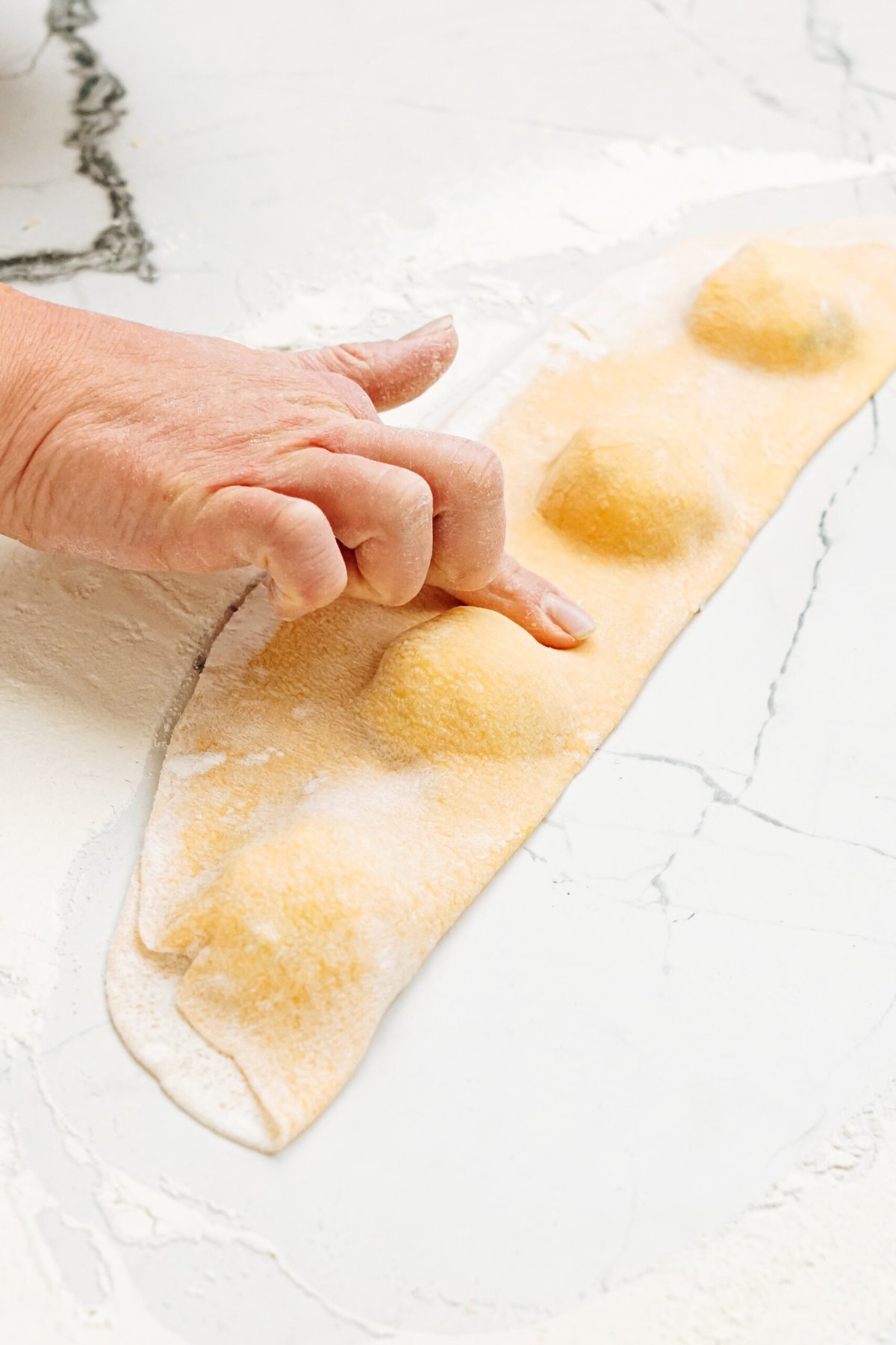 A person pressing dough around the edges of the filing, creating a pocket