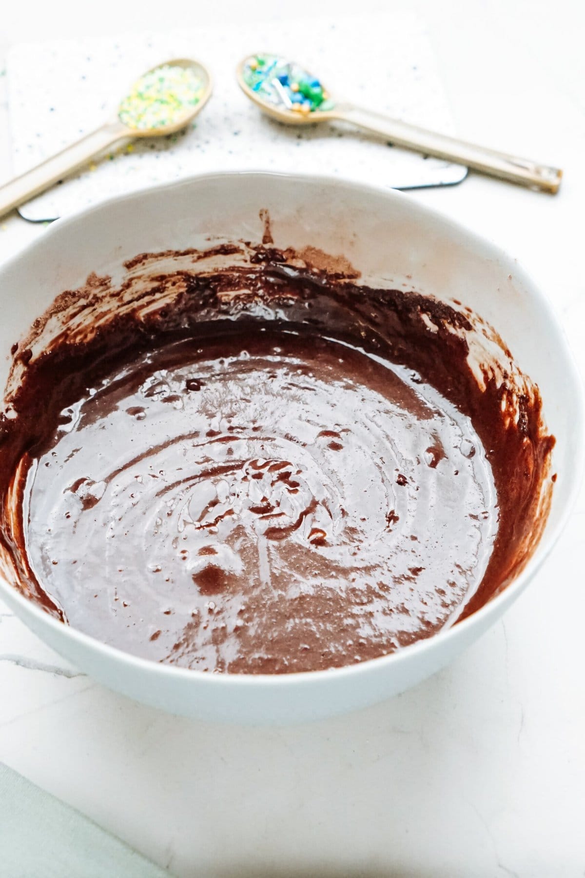A bowl of chocolate cake batter with spoons next to it.