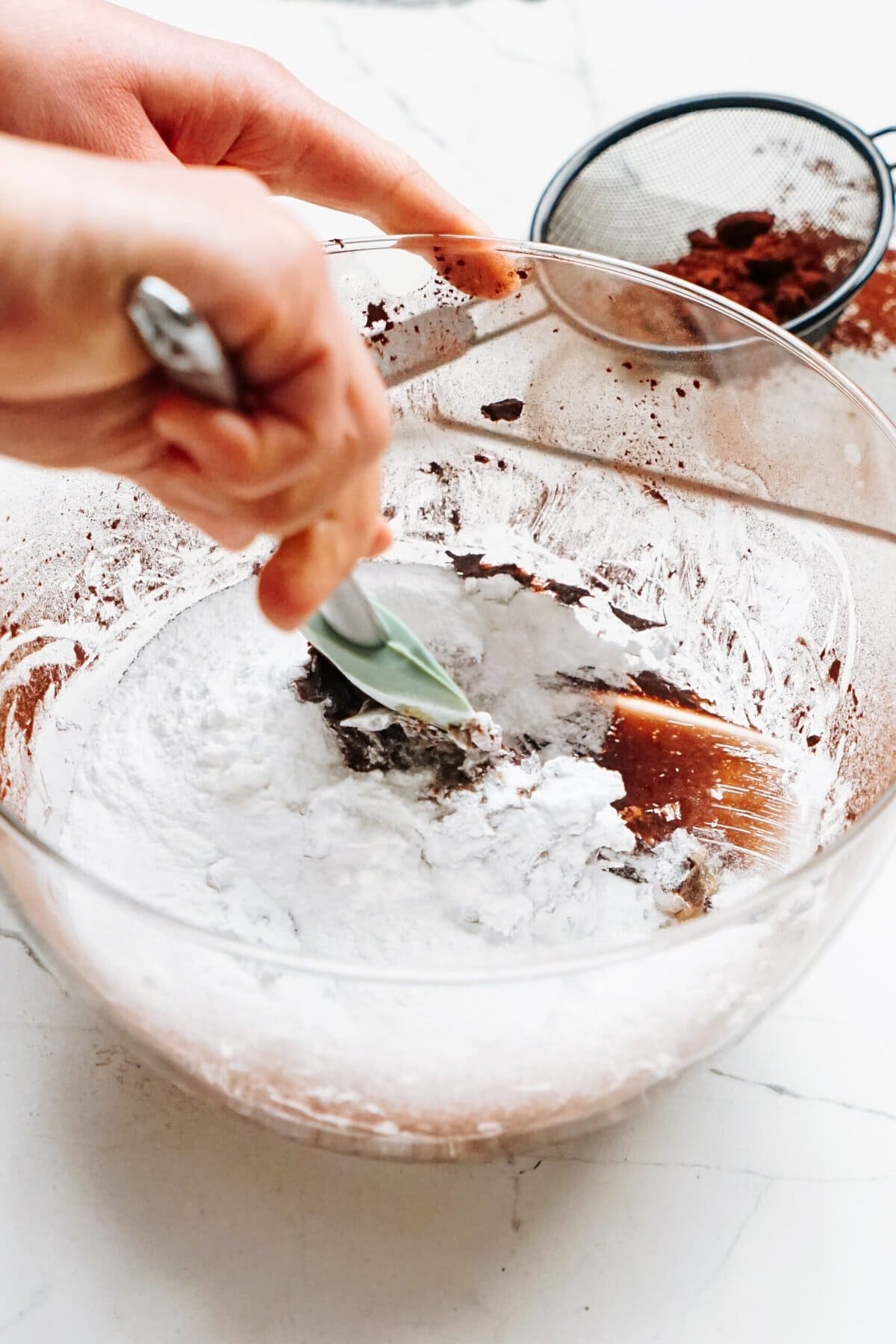 A person mixing ingredients in a glass bowl.