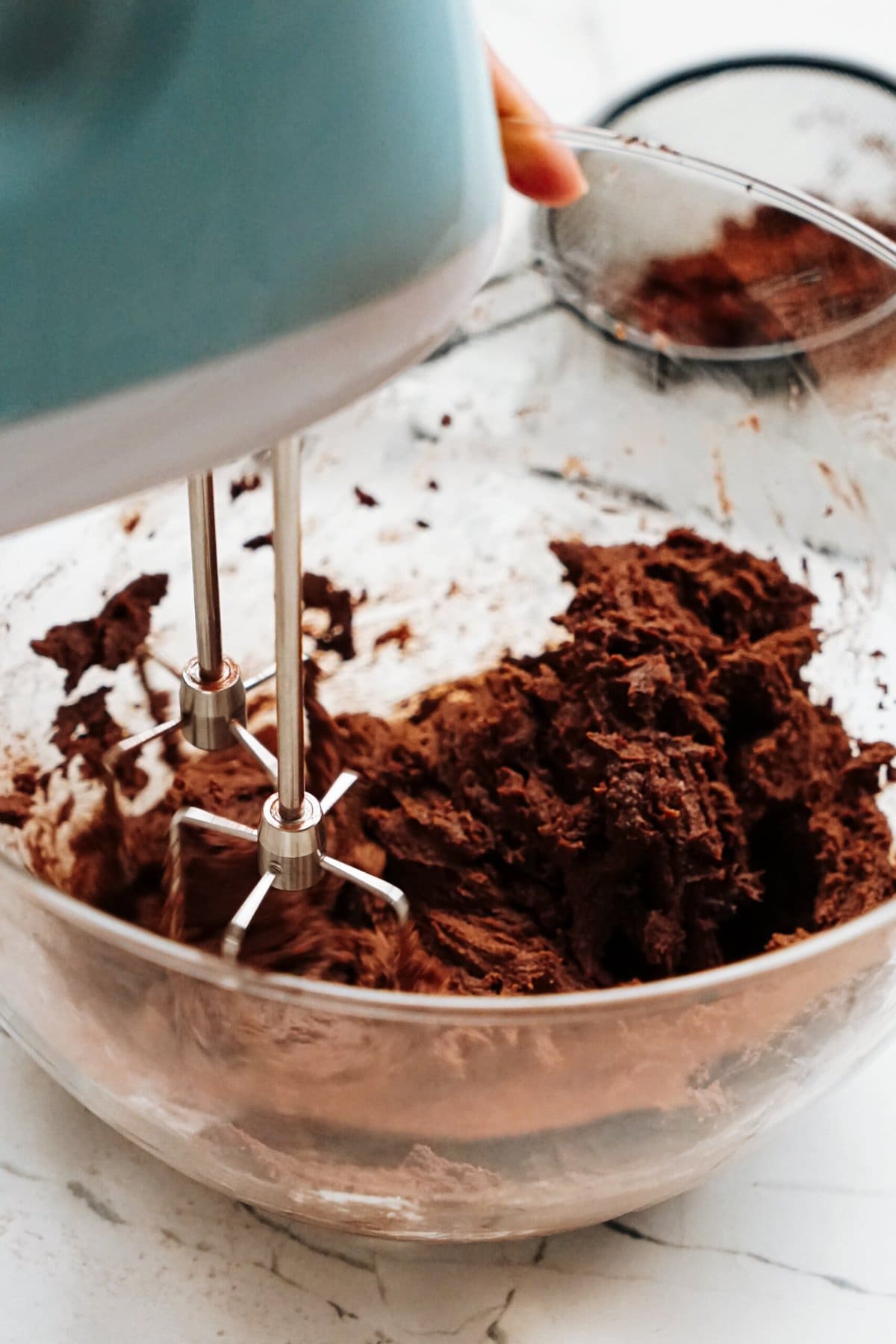 A person mixing chocolate in a bowl with a mixer.