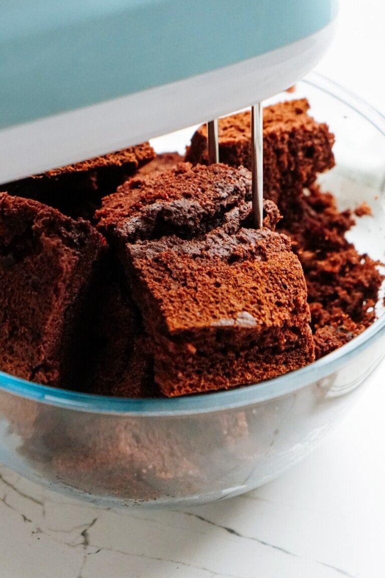Chocolate cake pieces in a bowl with a mixer.