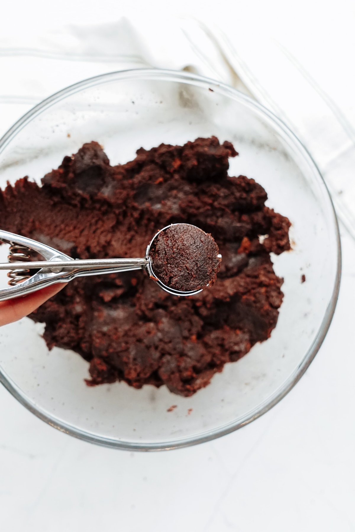 A person making a cake ball with a cookie scoop