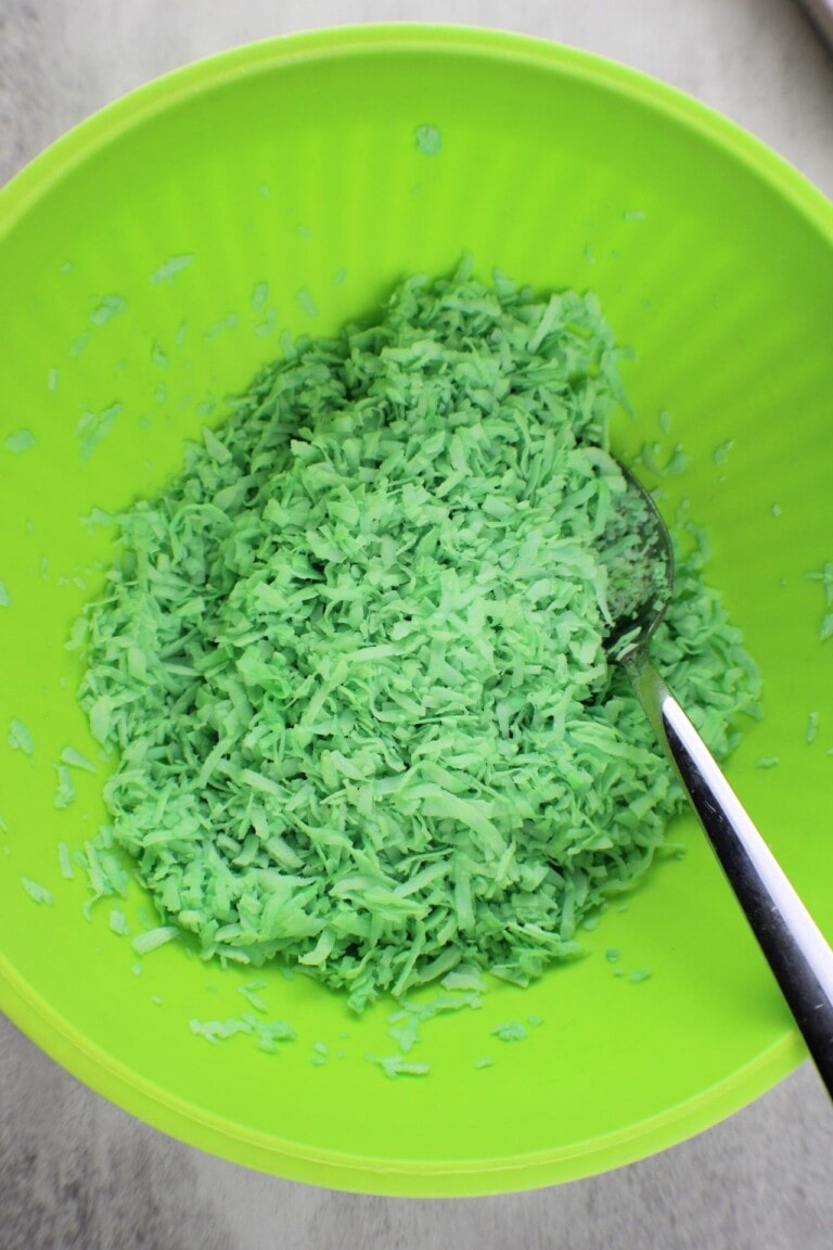 Green grated coconut in a lime green bowl with a spoon.