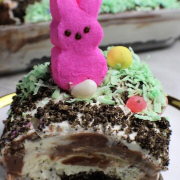 A slice of layered dessert topped with a pink marshmallow bunny and colorful sprinkles.