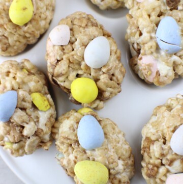 Plate of homemade Rice Krispie Treats, each topped with pastel-colored candy eggs.
