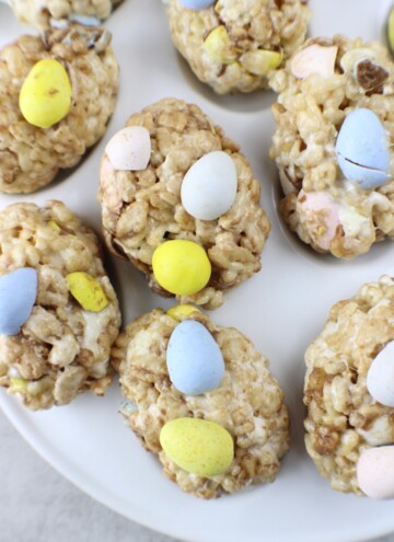 Plate of homemade Rice Krispie Treats, each topped with pastel-colored candy eggs.