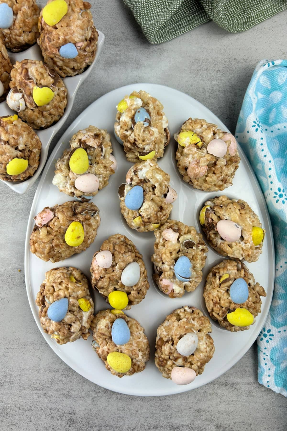Easter egg shaped Rice Krispie Treats with colorful candy eggs on a white plate.