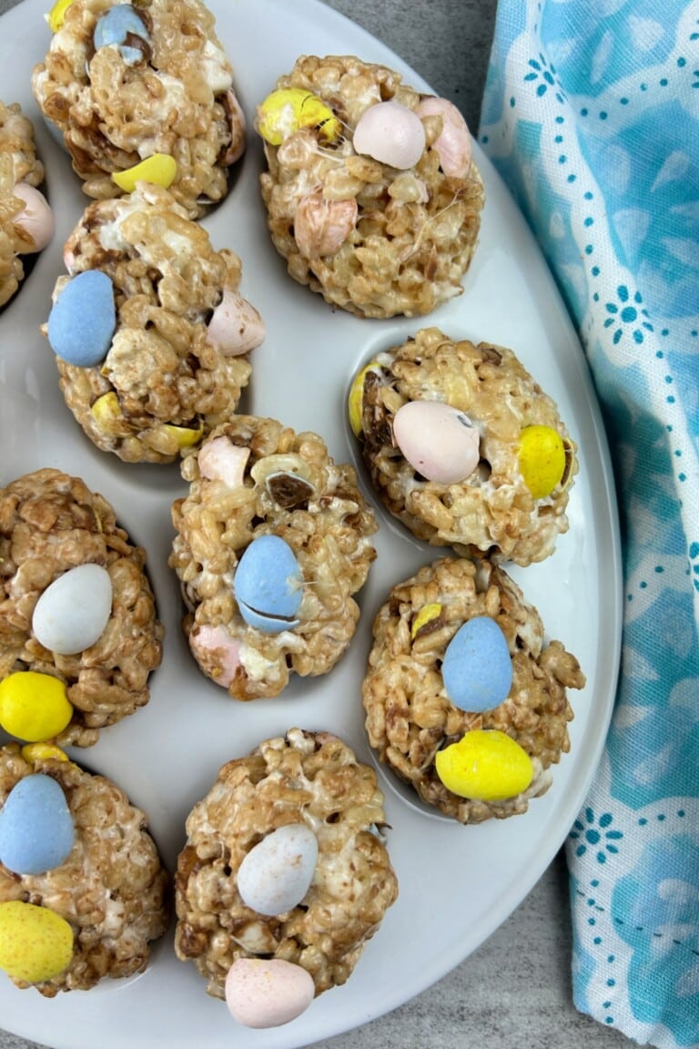Plate of homemade Rice Krispie Treats eggs decorated with pastel-colored candy eggs.