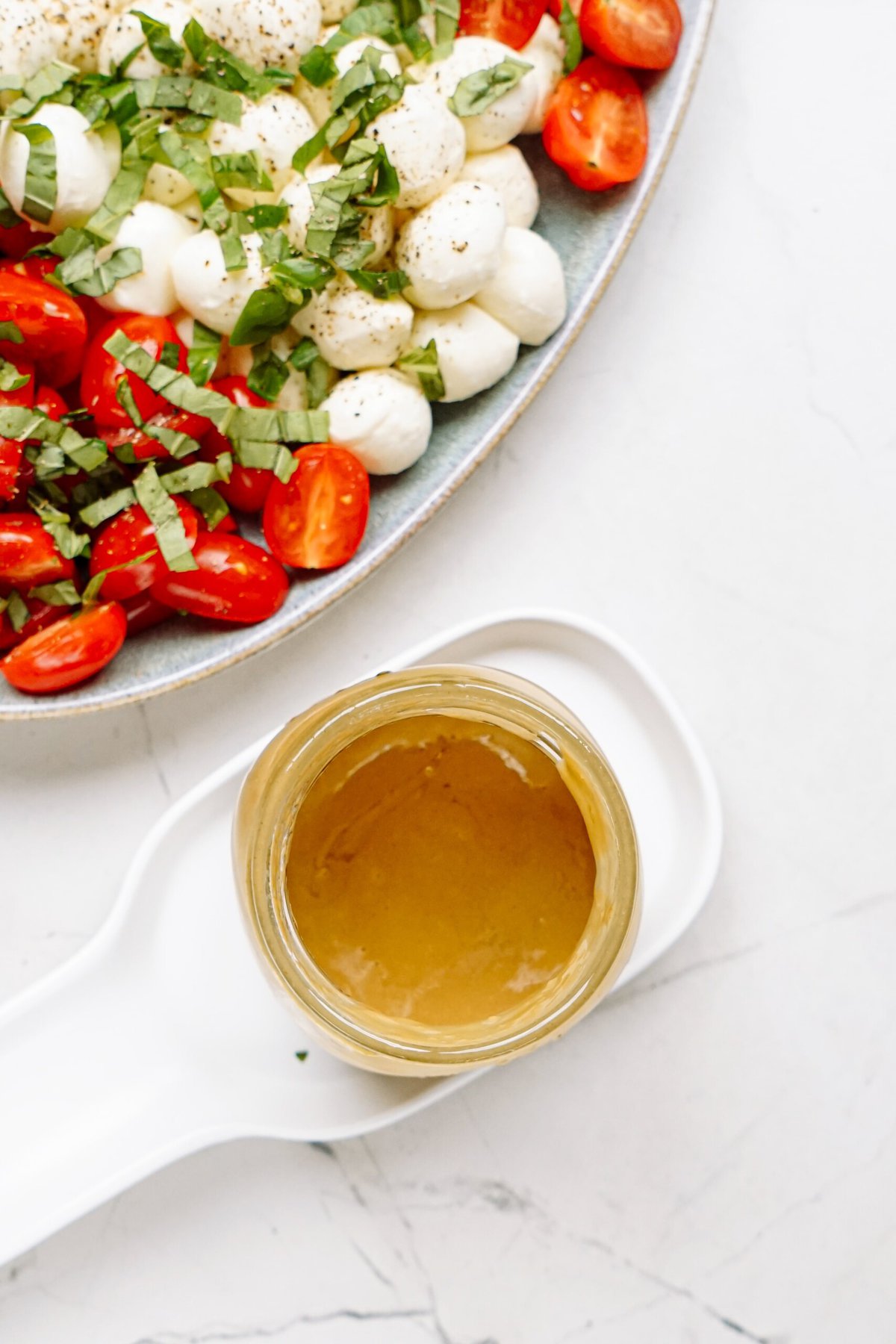 garlic mustard balsamic dressing next to a plate of tomatoes and mozzarella balls