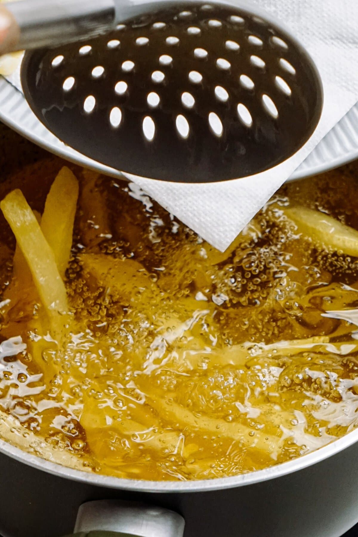 frites being added into a pot of hot oil