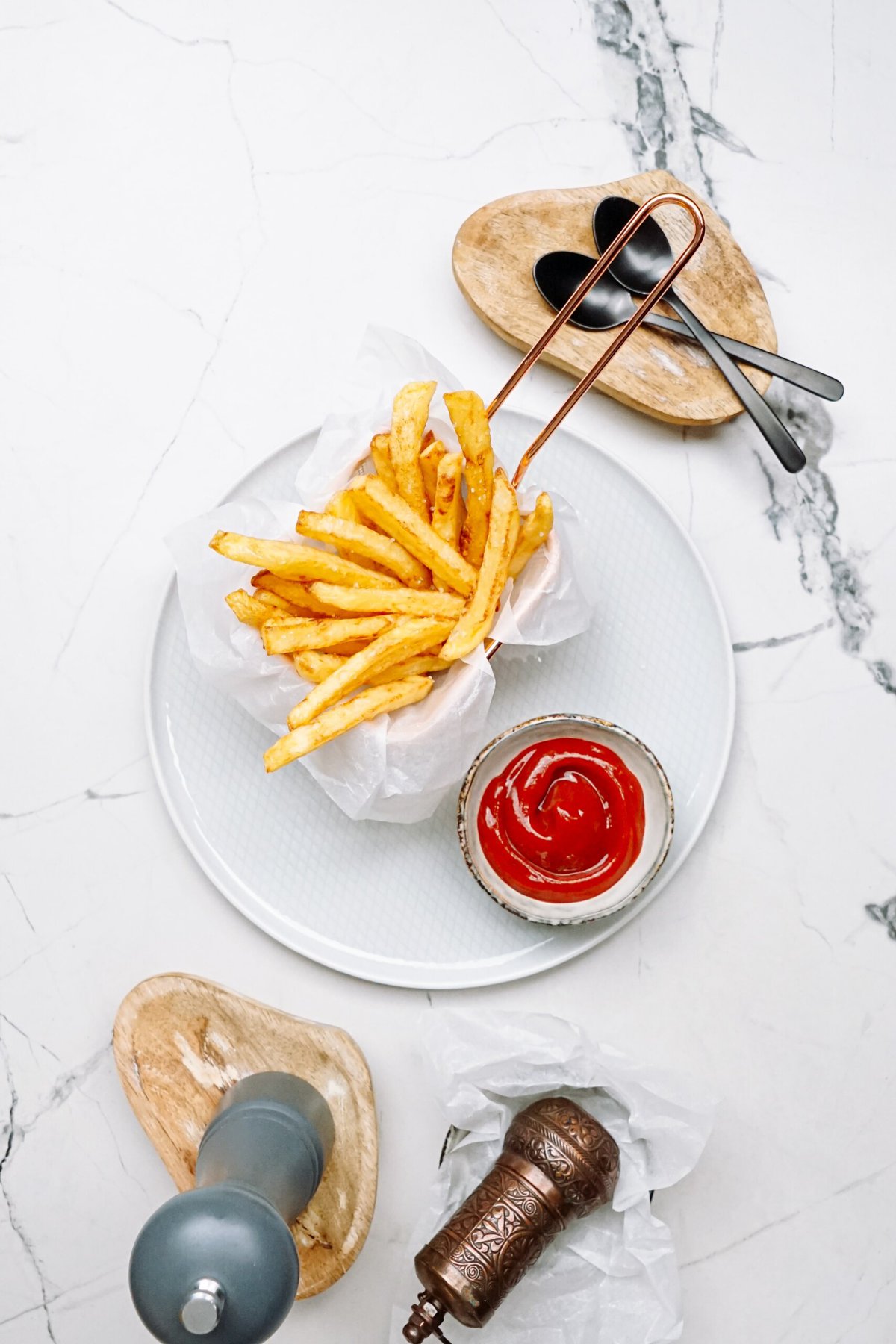 pomme frites arranged on a plate with a little cup of ketchup on a tablescape