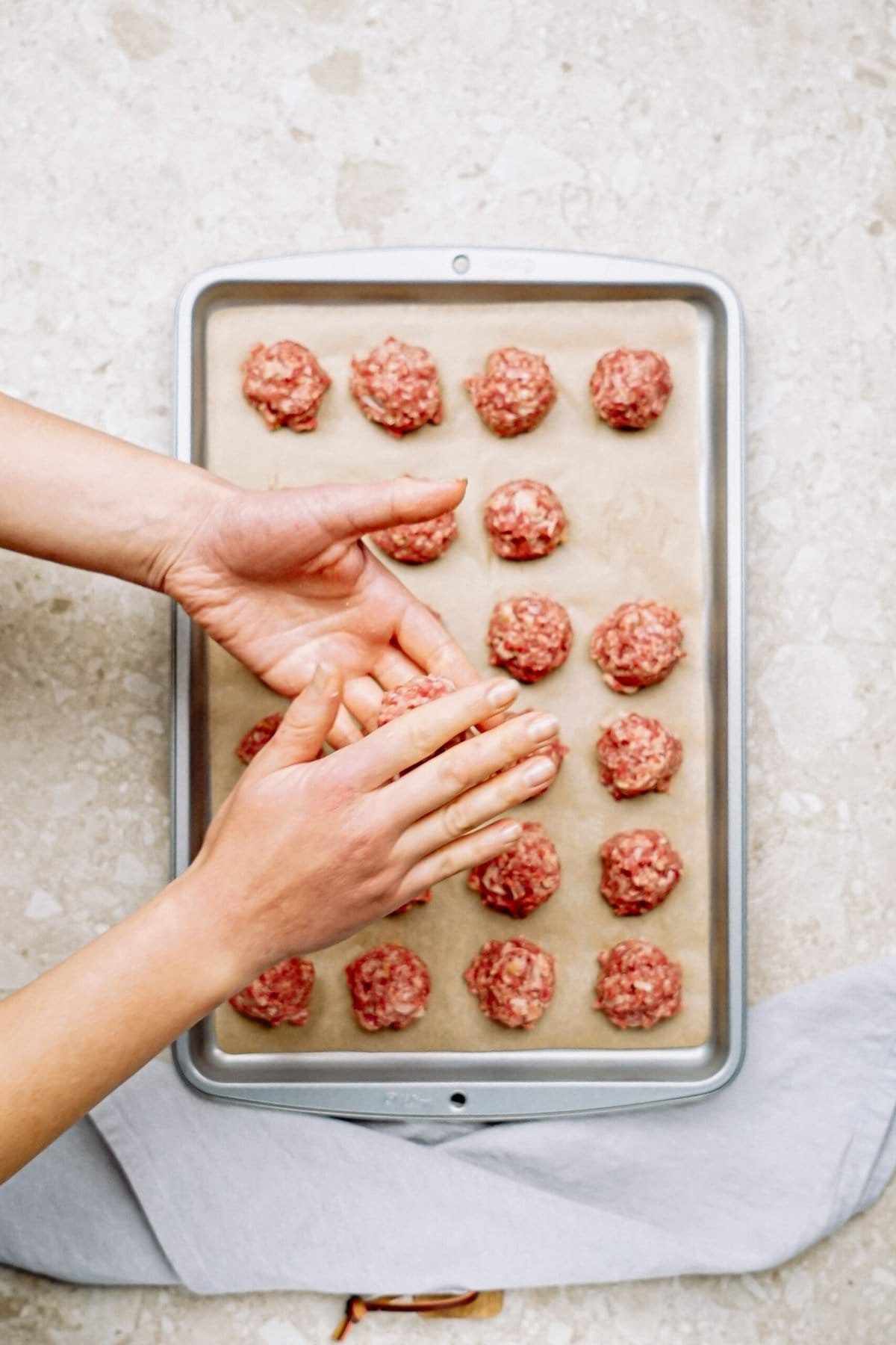 Preparing meatballs on a baking sheet.